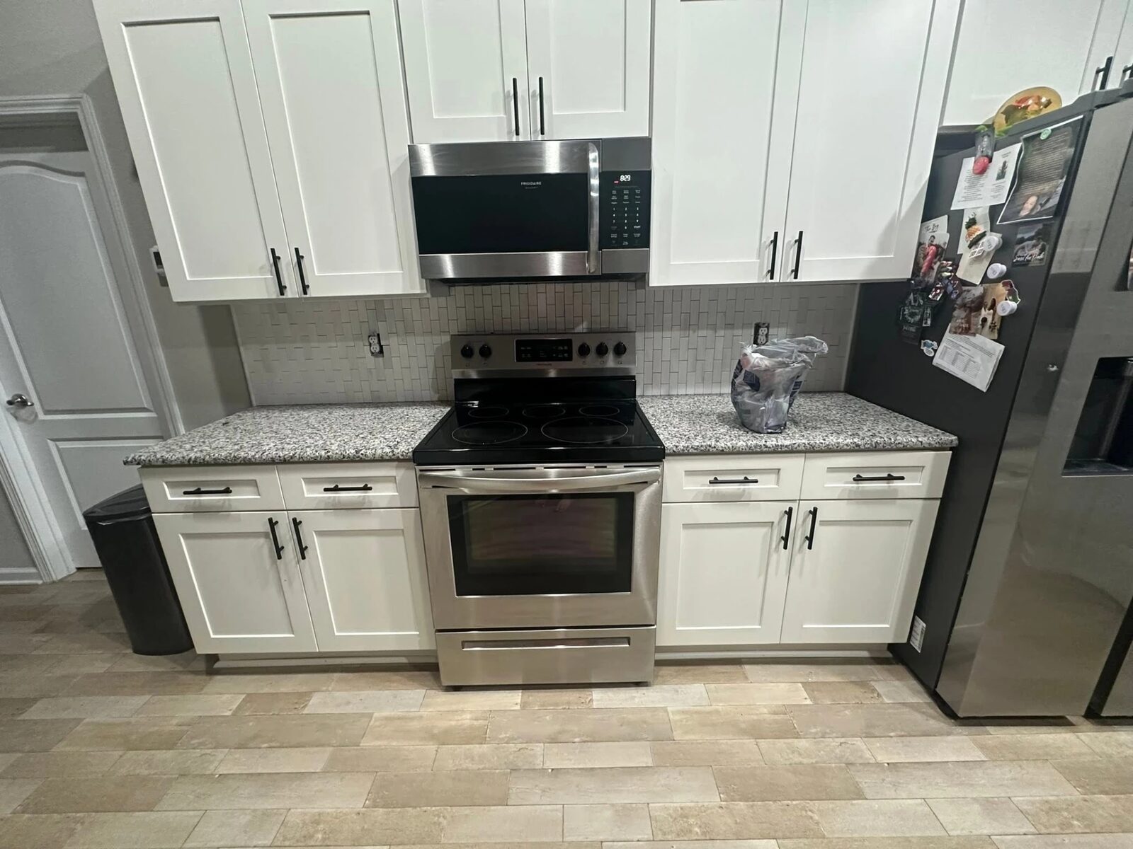 Finished kitchen with white shaker cabinets, granite counters and new tile backsplash