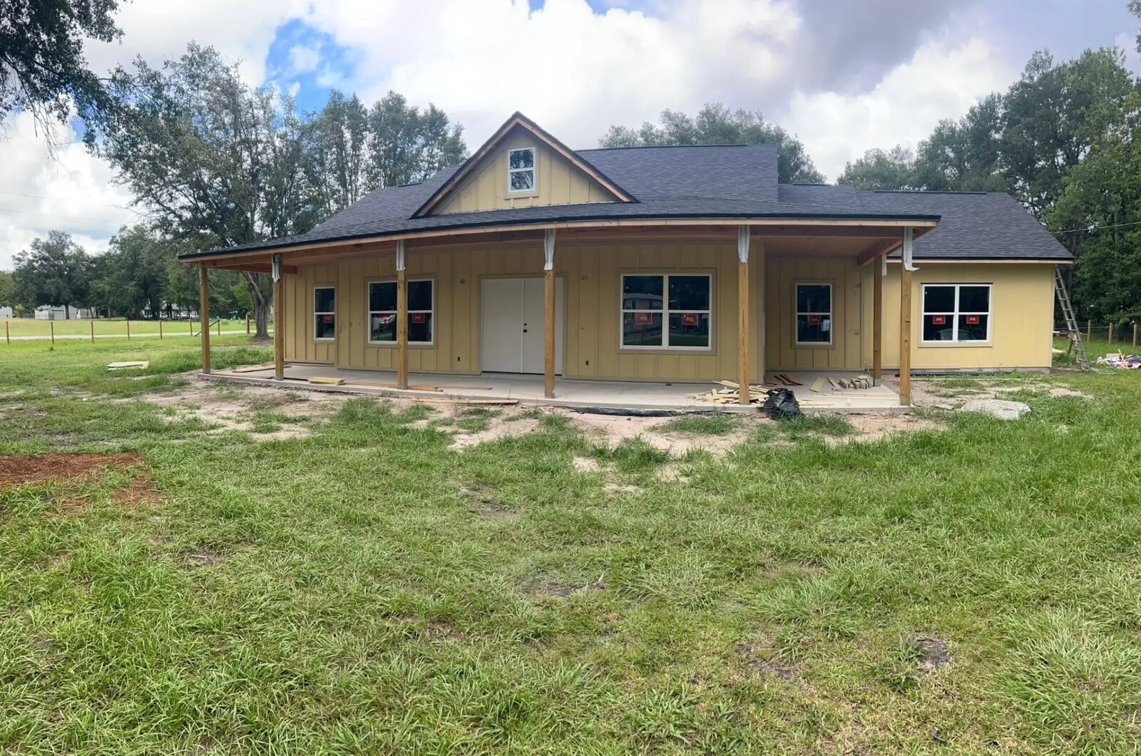 New custom home with wrap-around porch and board and batten siding under construction