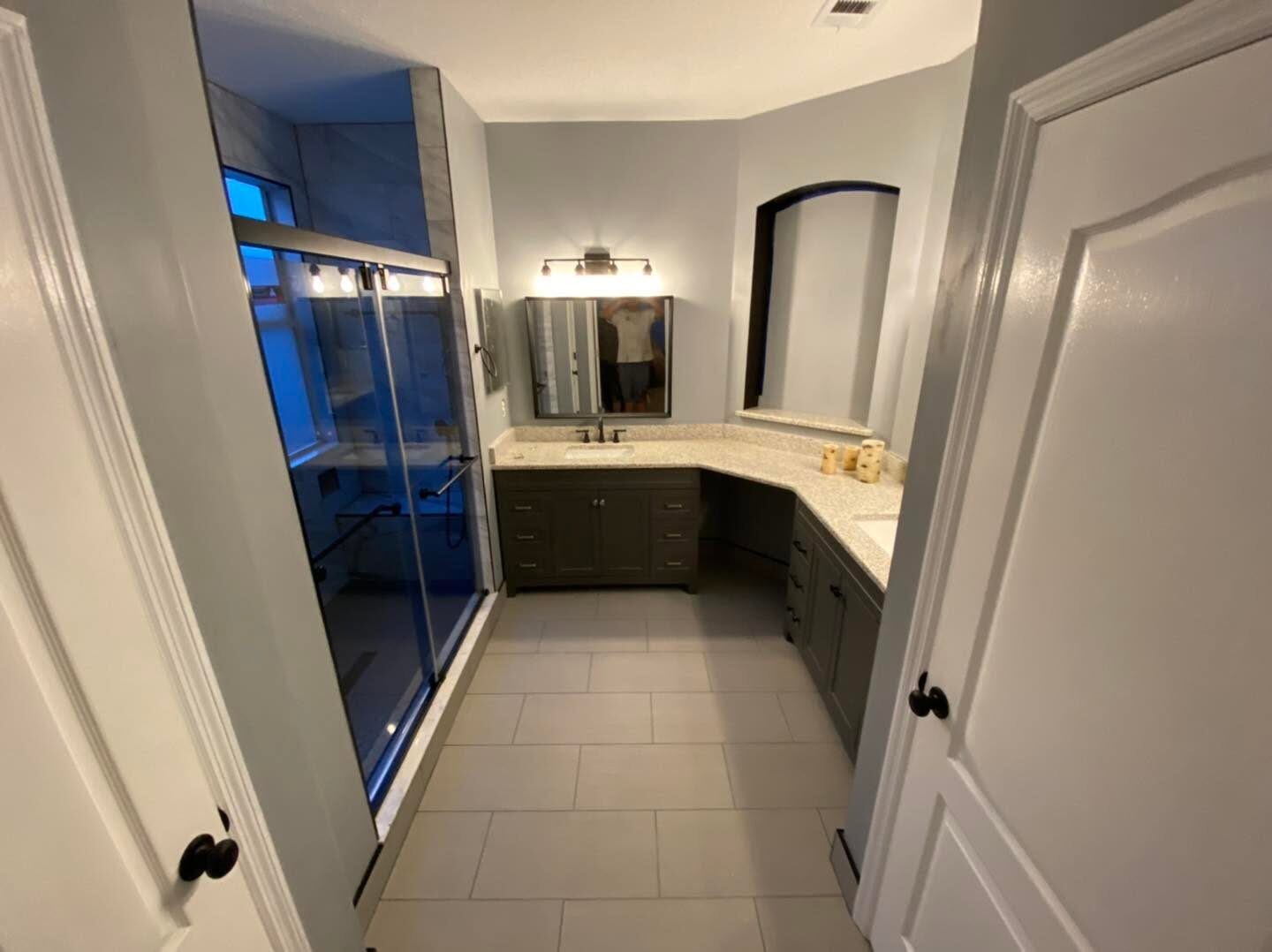 Finished bathroom with corner dual vanity, granite tops and large format tile flooring
